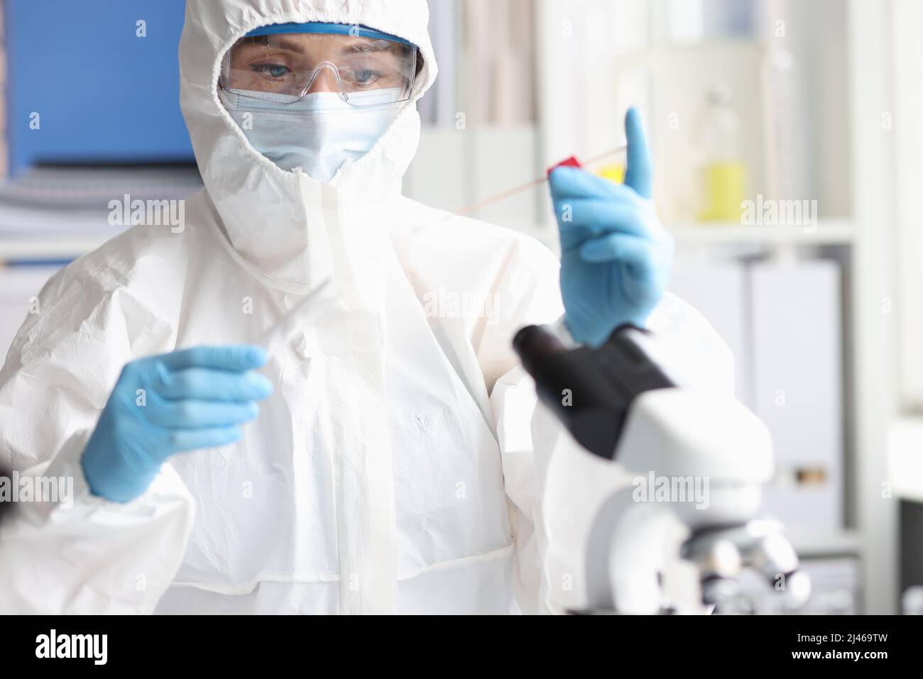 Scienziato in tuta protettiva e occhiali di protezione conduce la ricerca in laboratorio Foto Stock