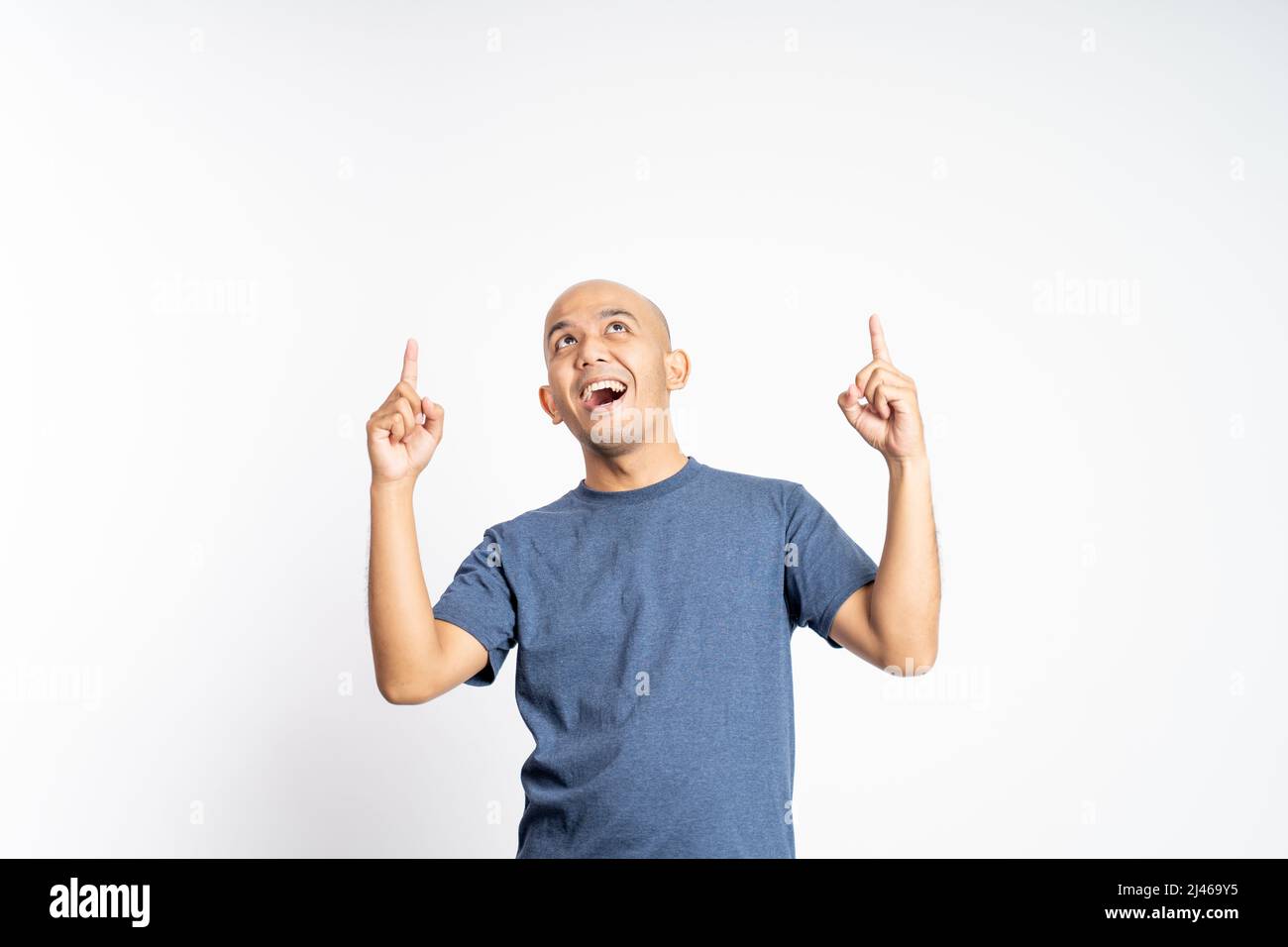 uomo calvo sorridente con un dito rivolto verso l'alto in un punto vuoto Foto Stock