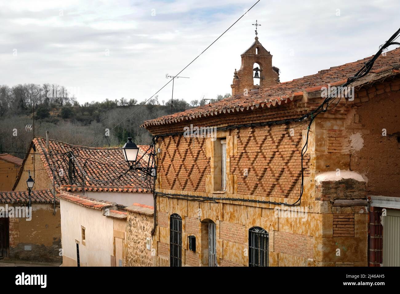 Fantasia mattoni a forma di diamante su una casa a Venialbo, Spagna. Il campanile della chiesa cattolica sullo sfondo Foto Stock