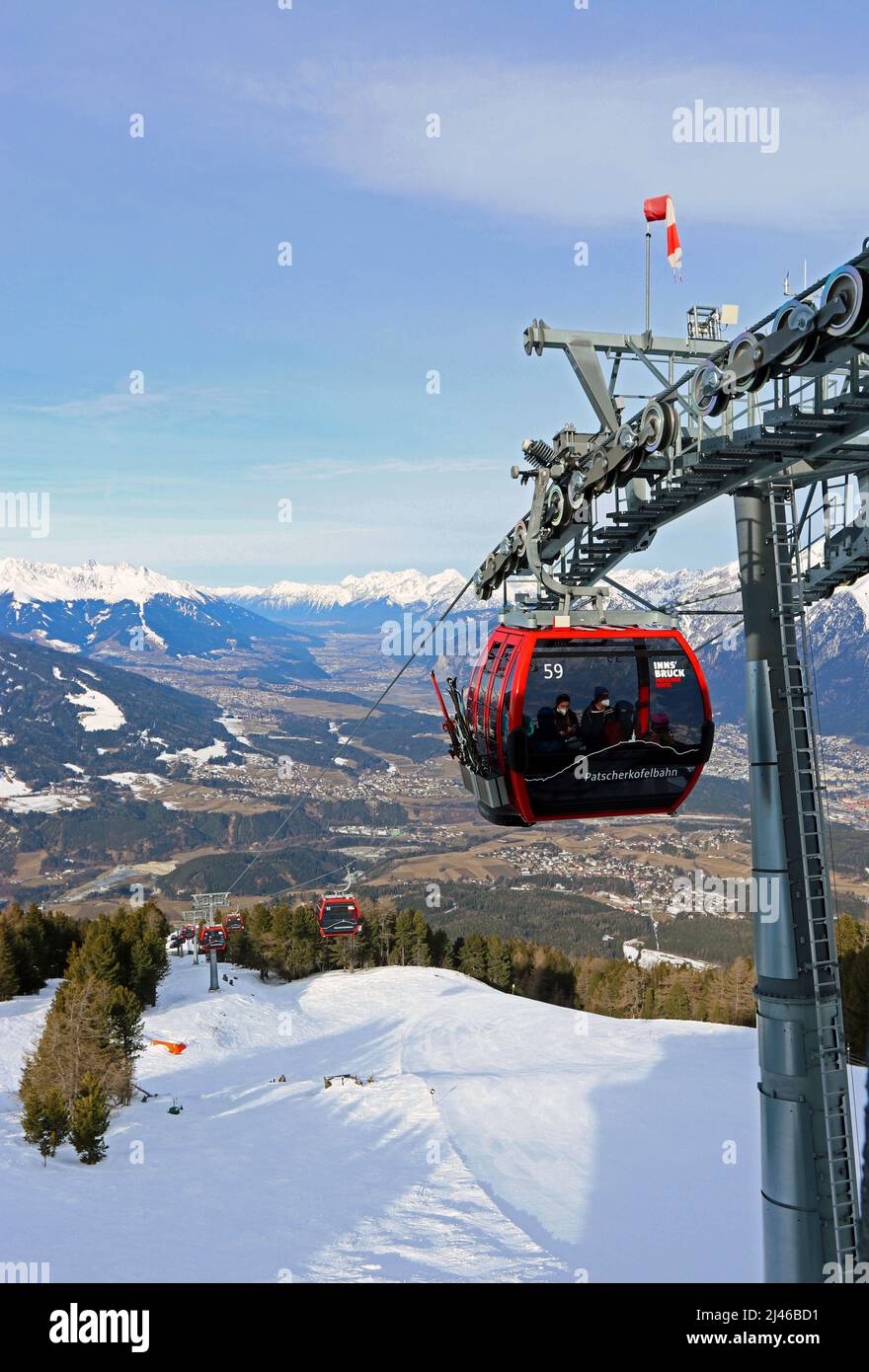 La funivia di Patscherkofelbahn si avvicina alla stazione di Bergstation; Innsbruck si estende lungo la valle dell'Inn sottostante; la catena montuosa Nordkette alle spalle Foto Stock