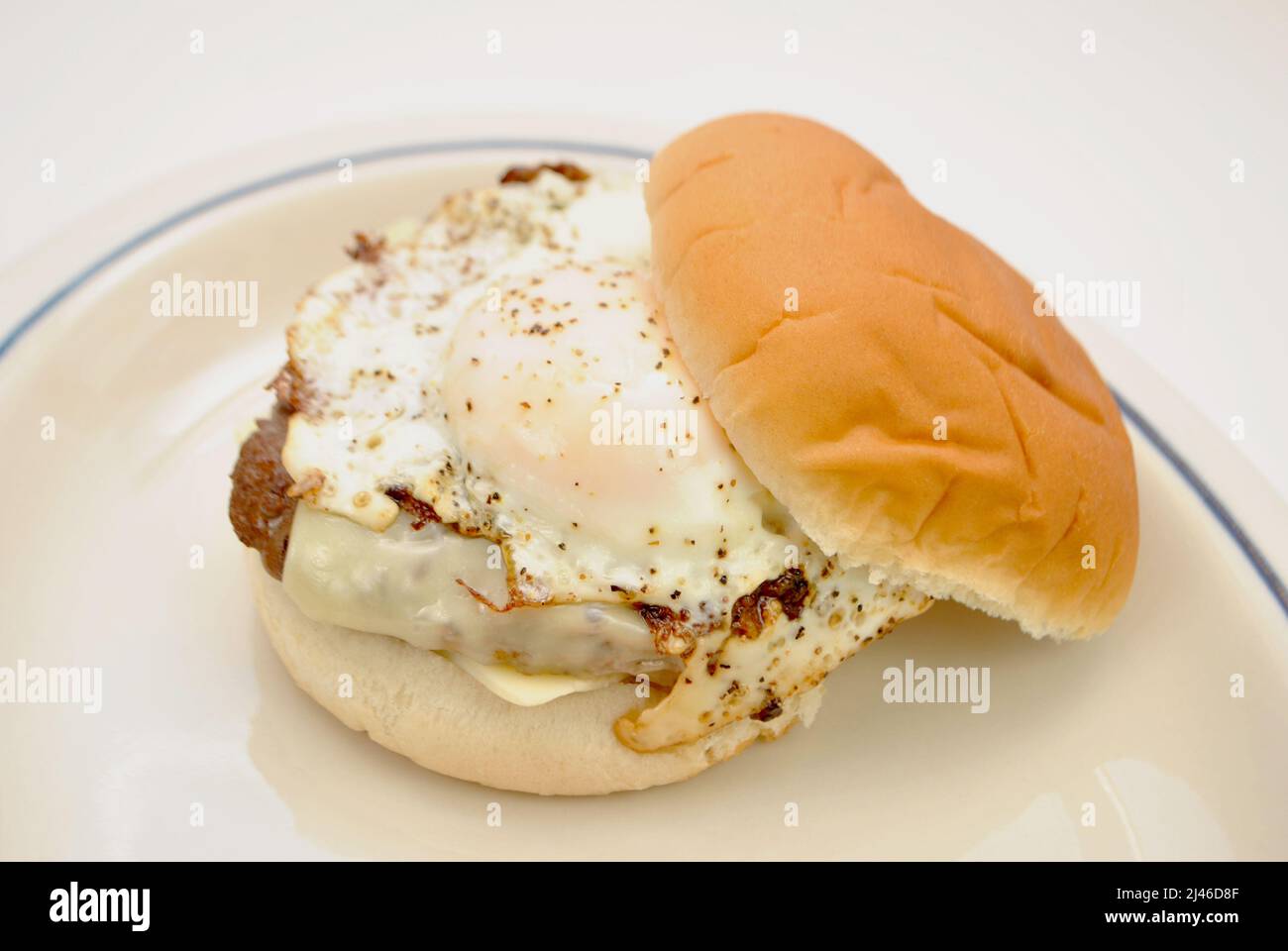 Uovo fritto in cima a un raro Cheeseburger succoso Foto Stock