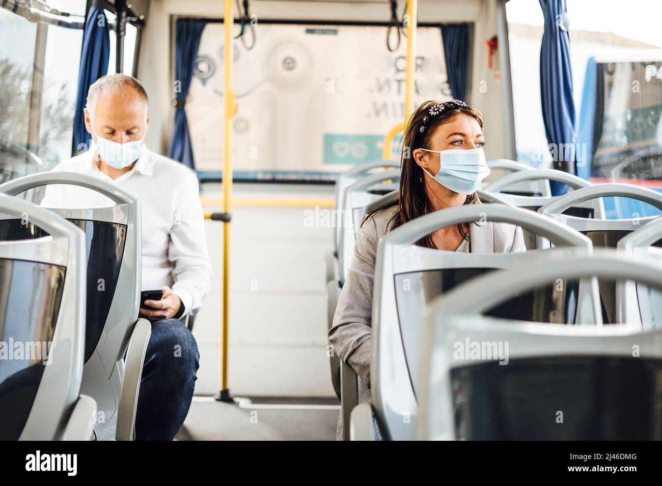 Viaggiatori che indossano maschere protettive che viaggiano con autobus pubblico Foto Stock