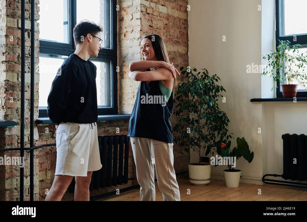 Felice giovane coppia di ballerini in voga in activewear comunicando tra loro in moderno studio di coreografia prima della ripetizione Foto Stock