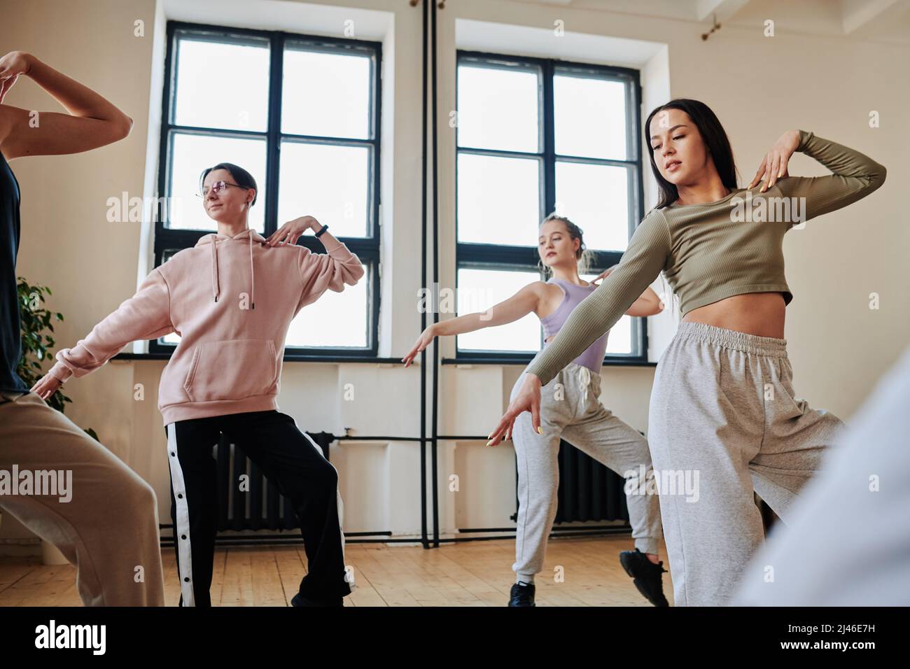 Gruppo di adolescenti attivi e contemporanei che praticano movimenti di danza del voga mentre si allenano in studio loft o sala da ballo Foto Stock