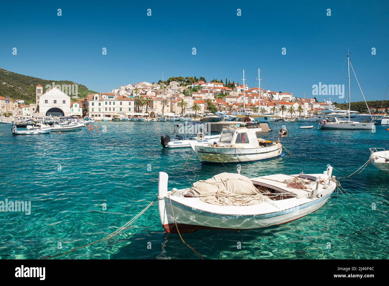 Porto con barche in acque turchesi sull'isola di Hvar, Croazia con la città vecchia sullo sfondo. Località turistica. Destinazione estiva Foto Stock