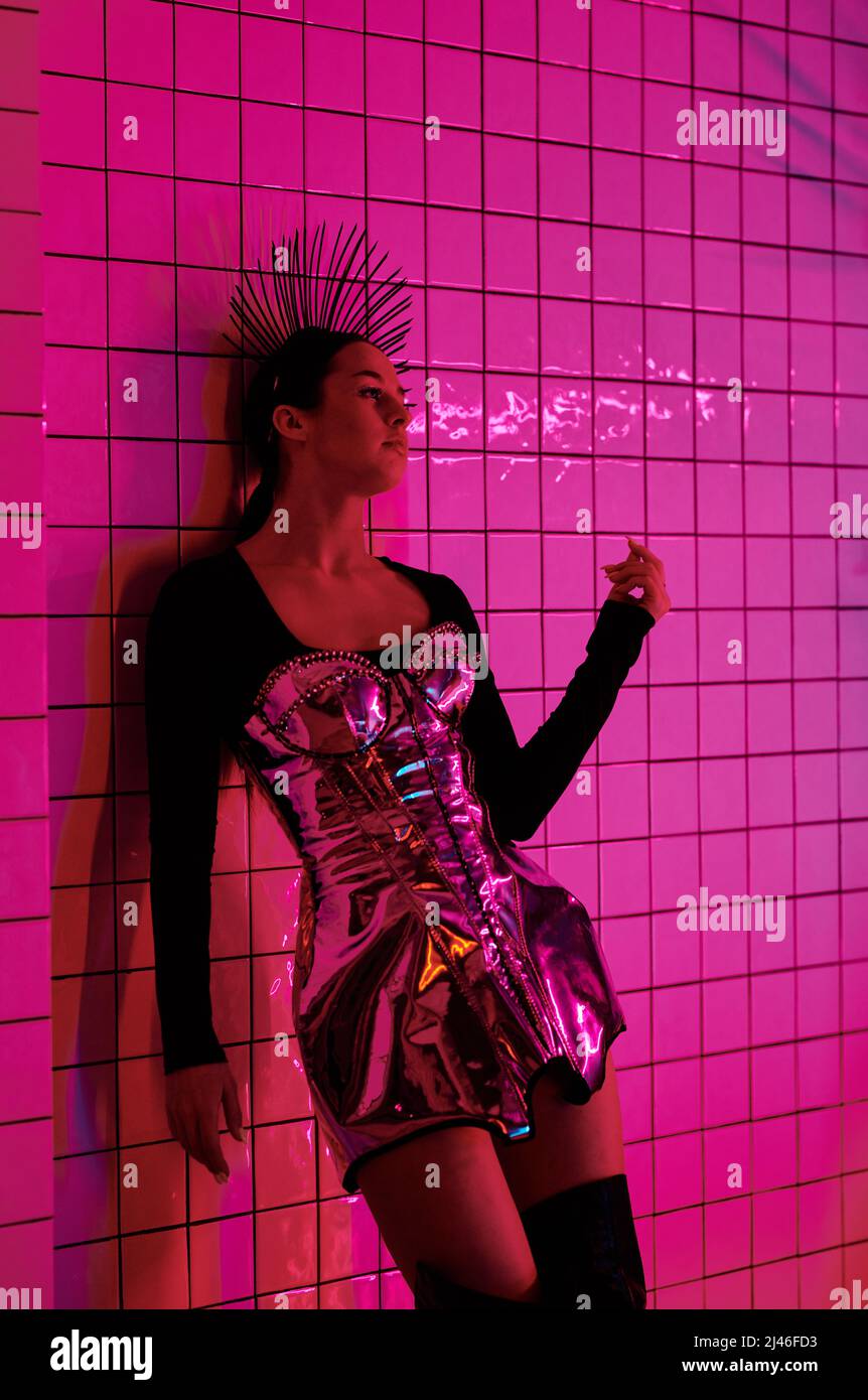 Teenager femminile contemporaneo in abito futuristico scena che partecipa a performance di danza VOGUE o sfilata di moda in nigh club Foto Stock