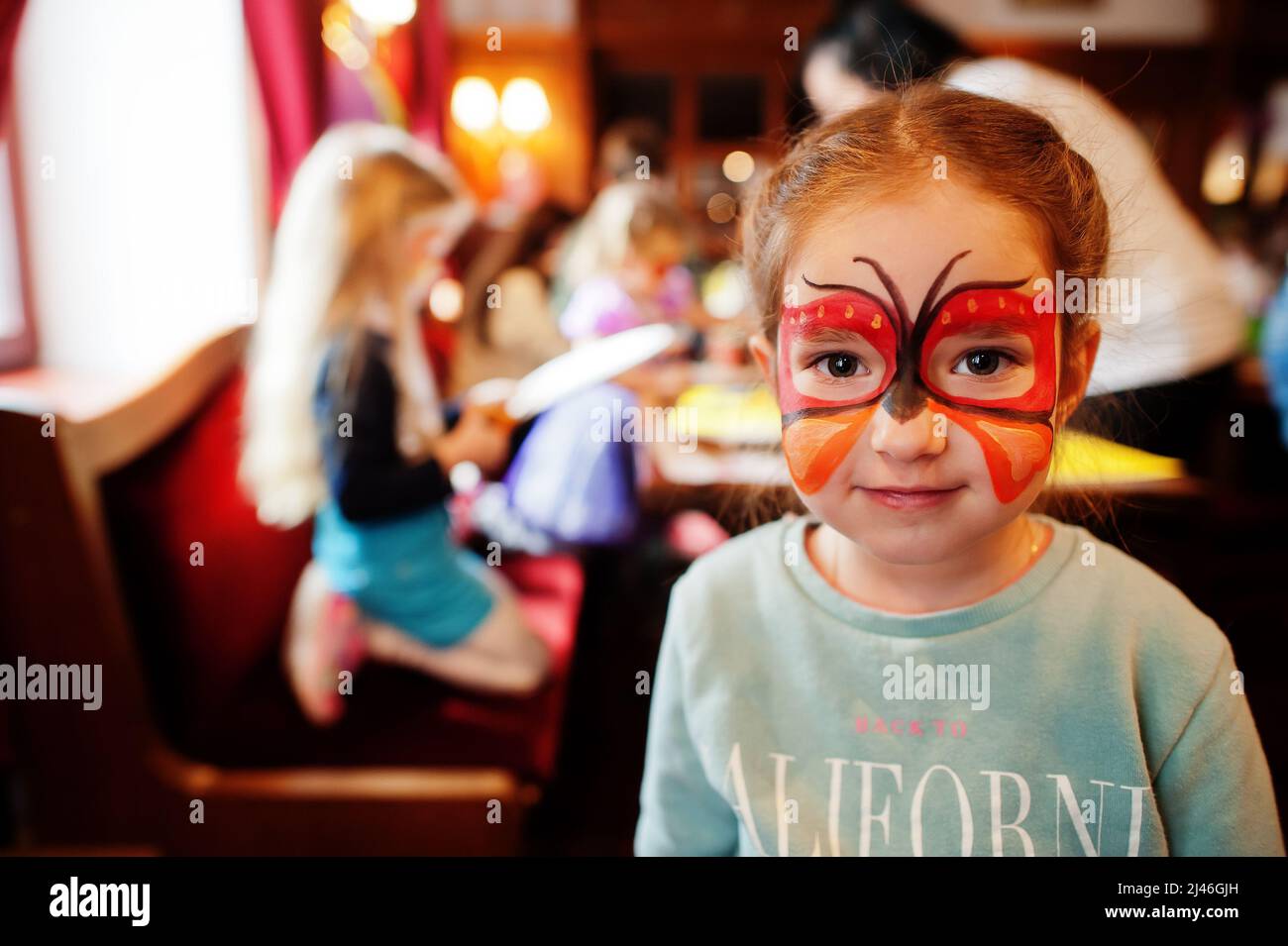 Preparazione al concetto di Pasqua. Bambina con farfalla acqua compongono sul viso. Foto Stock