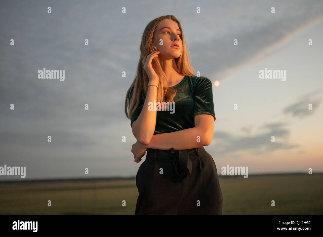 Giovane donna che guarda il tramonto su una terra desolata Foto Stock