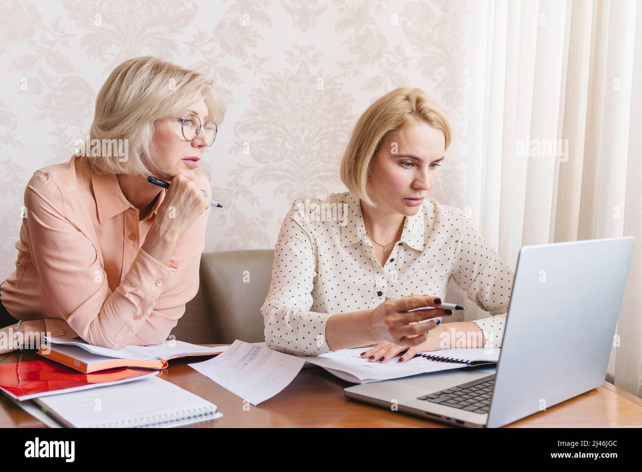 Le donne d'affari mature discutono i documenti nell'ufficio domestico. Foto Stock
