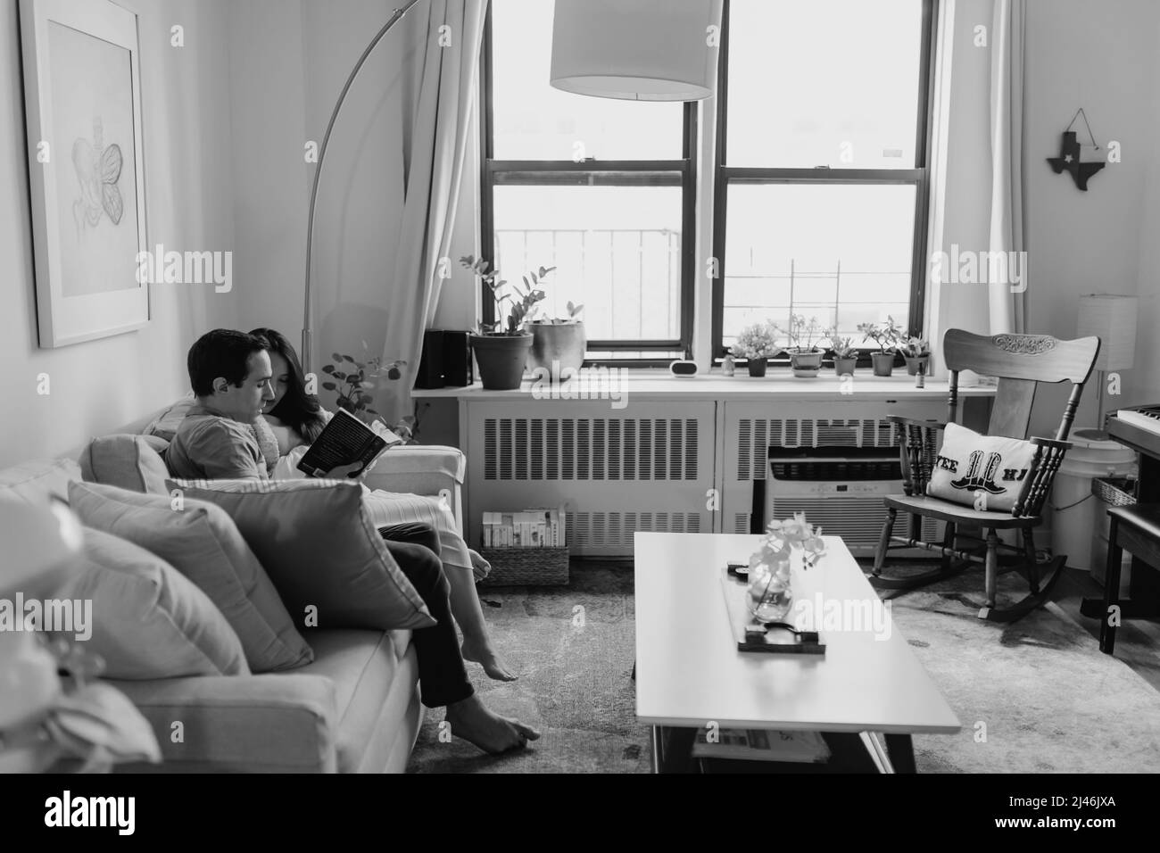 Aspettandosi che i genitori si rilassino e leggano sul divano del soggiorno Foto Stock