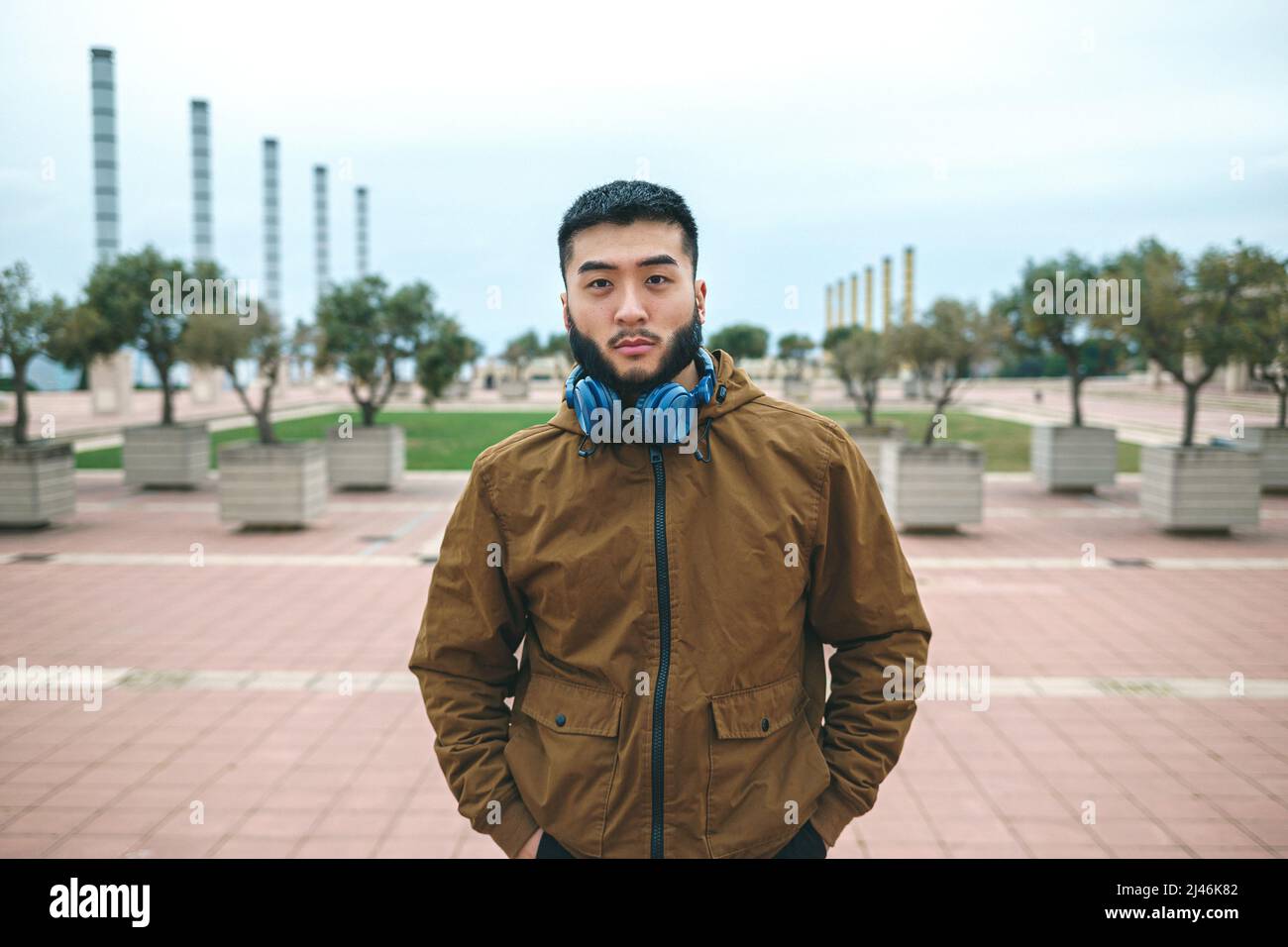 Uomo etnico serio con cuffie sul collo nel parco cittadino Foto Stock