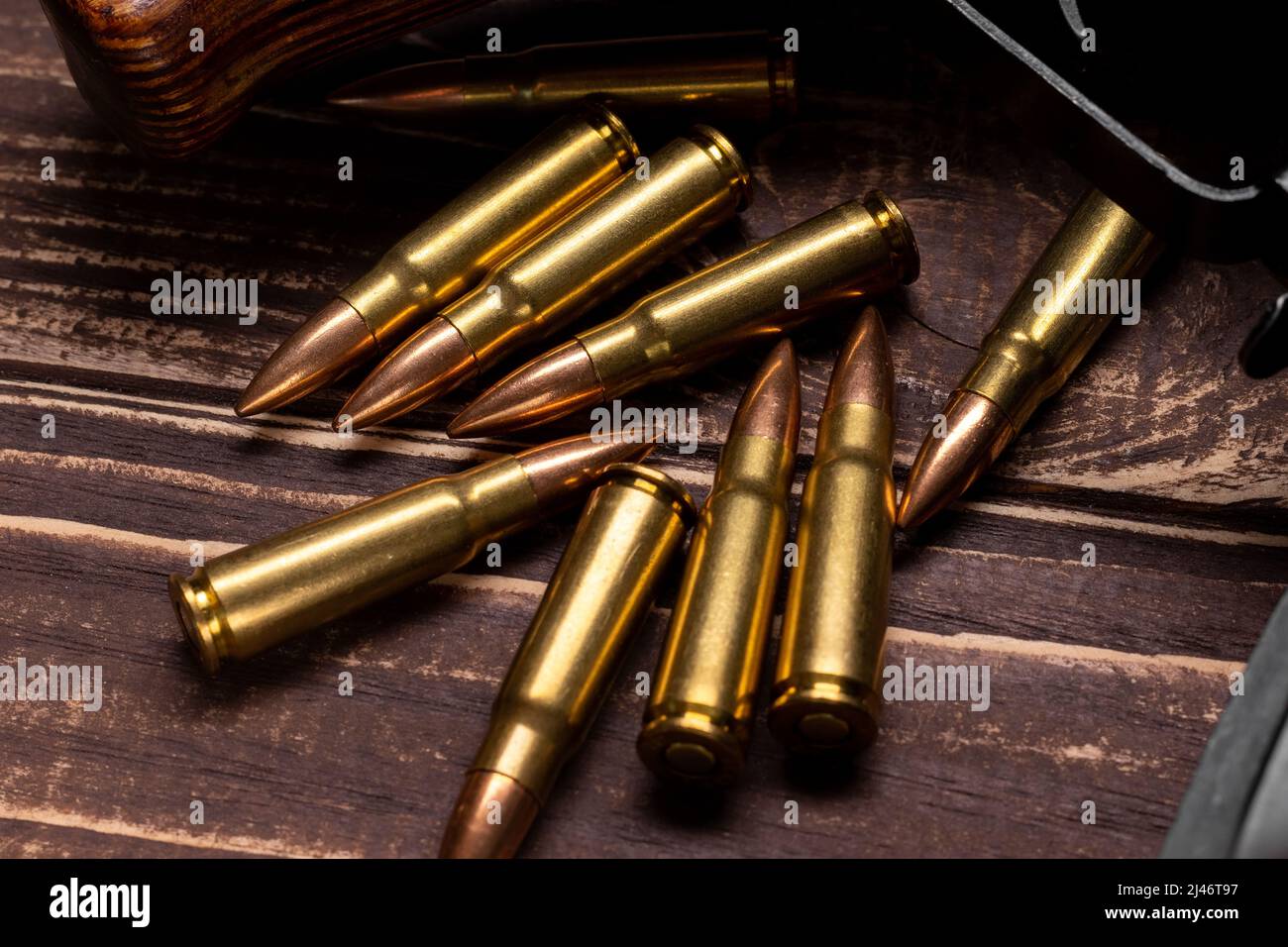 Proiettili e fucile d'assalto Kalashnikov su sfondo di legno. Cartucce calibro 7,62 per closeup ak 47. Messa a fuoco selettiva Foto Stock