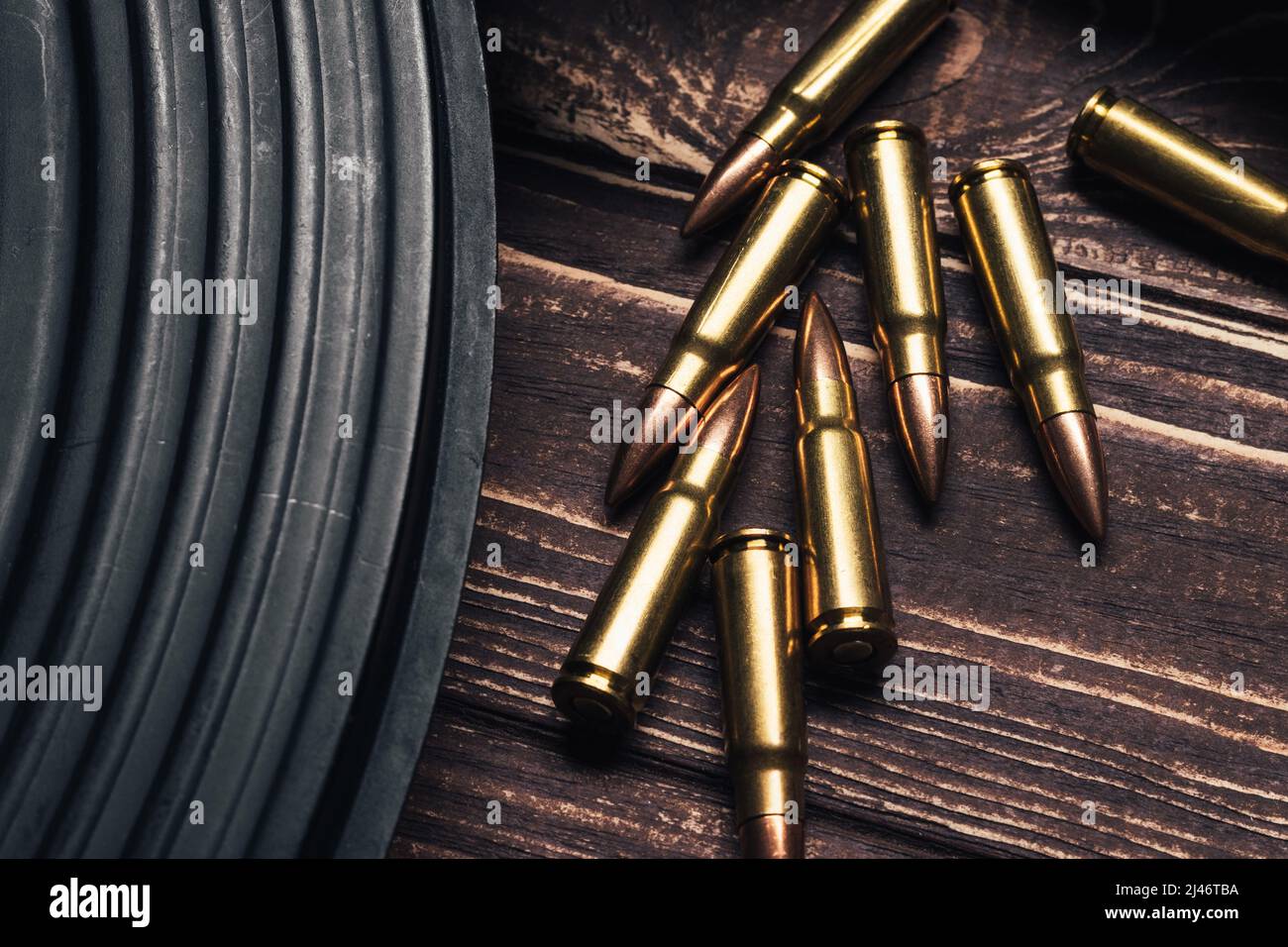 Proiettili e fucile d'assalto Kalashnikov su sfondo di legno. Cartucce calibro 7,62 per closeup ak 47. Messa a fuoco selettiva Foto Stock