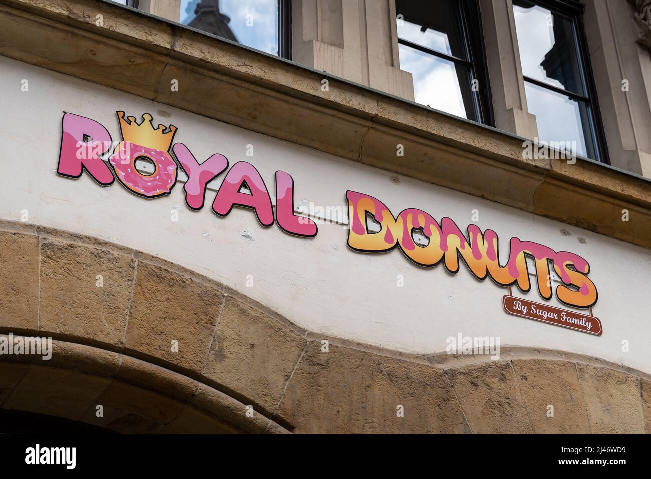 Logo del negozio Royal Donuts sulla facciata di un edificio. Segno di affari di franchising e buon marchio visibile in una strada. Fronte di una vecchia casa in città. Foto Stock