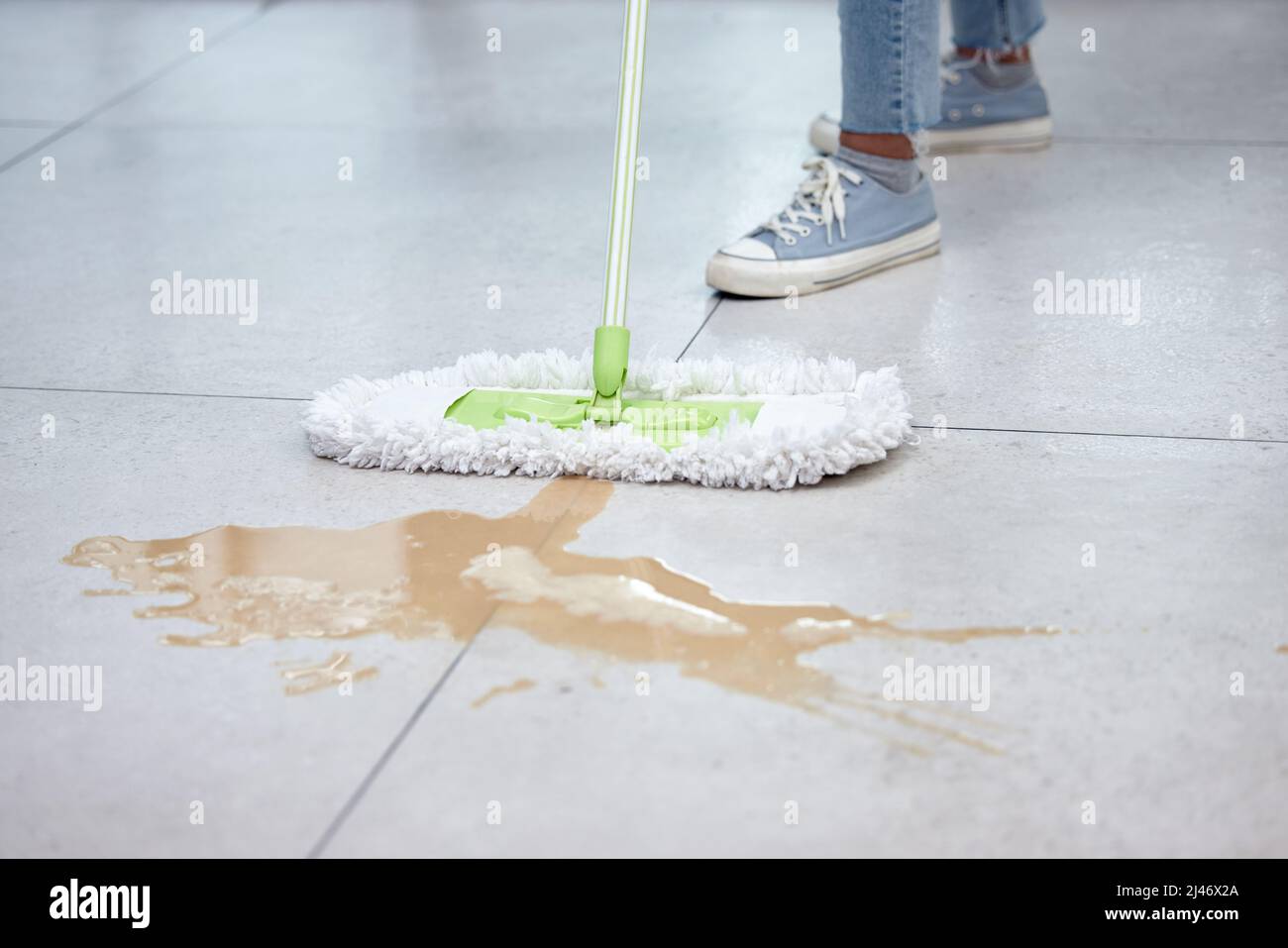 Non credo di aver versato di nuovo il caffè. Scatto di una donna che mopping il suo pavimento. Foto Stock