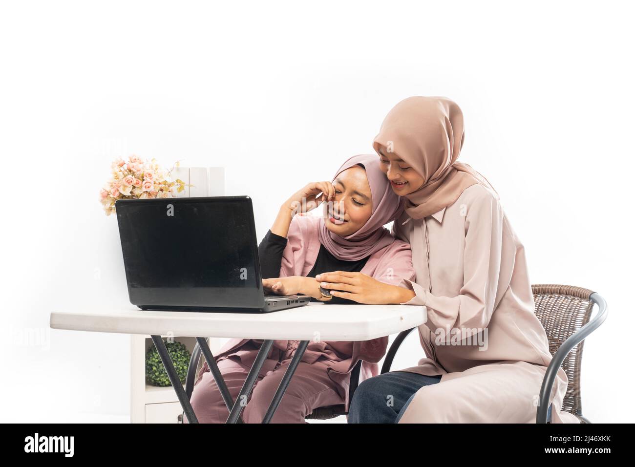 musulmana femmina che conforto la sua triste amica mentre lavora sul suo laptop Foto Stock