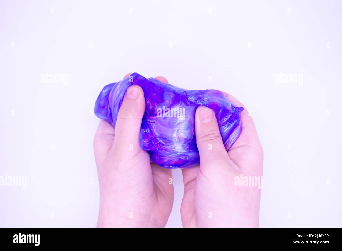Primo piano di gioco con due colori blu e rosa slime in qualcuno mani su uno sfondo bianco. Il muco è schiacciato, teso, strappato e schiacciato a mano Foto Stock