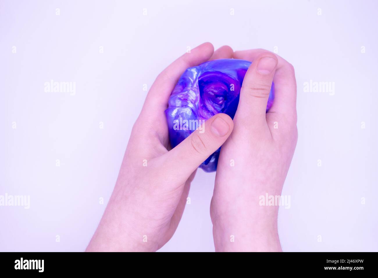 Primo piano di gioco con due colori blu e rosa slime in qualcuno mani su uno sfondo bianco. Il muco è schiacciato, teso, strappato e schiacciato a mano Foto Stock