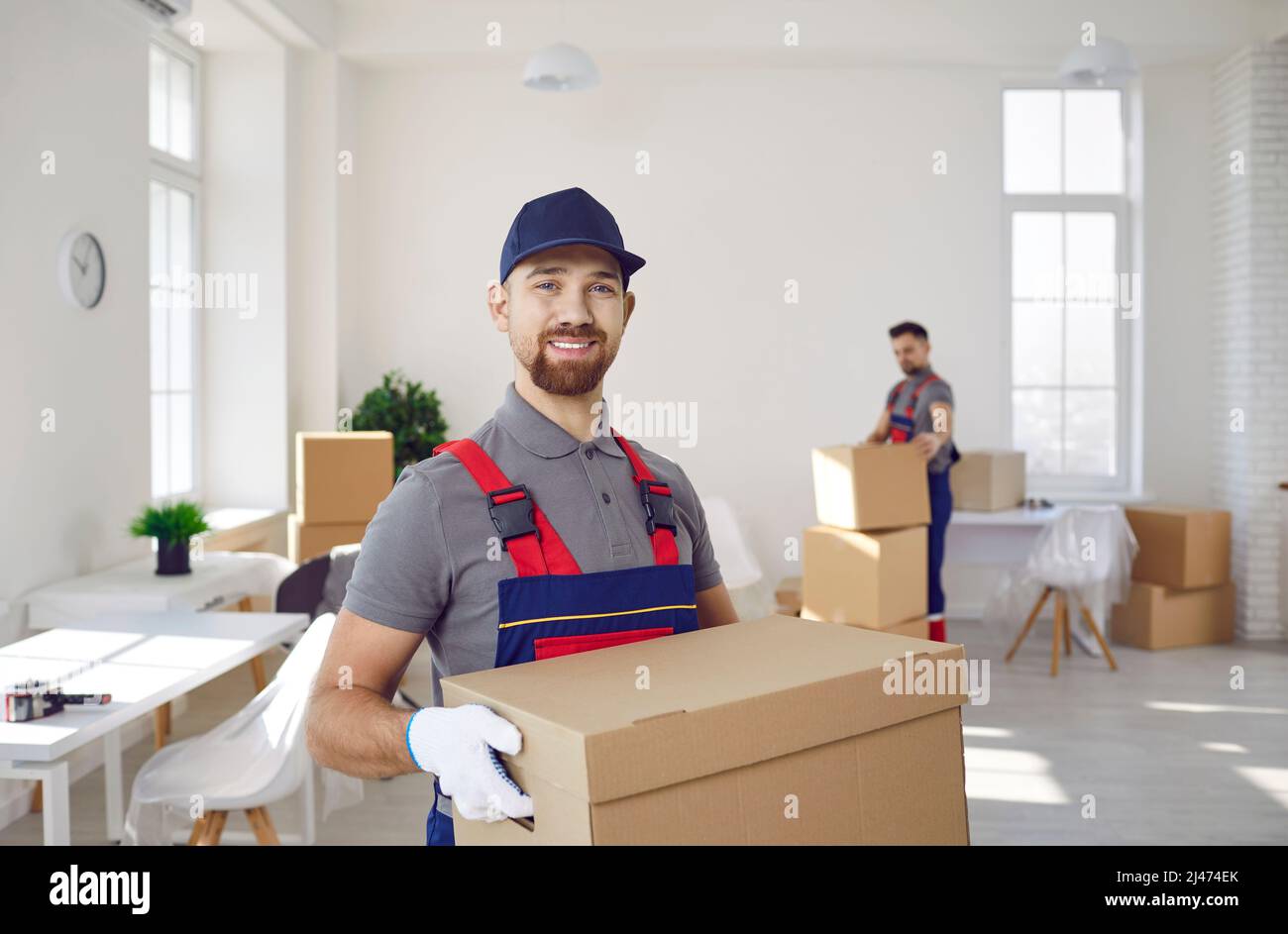 Ritratto di buon camion servizio di consegna lavoratore che tiene scatola di cartone e sorridente Foto Stock
