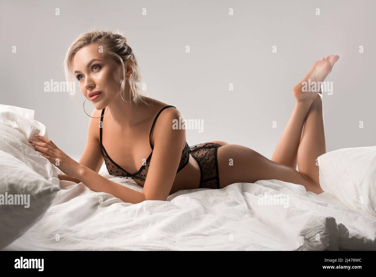 Donna sensuale sognante in lingerie nere sdraiata sul letto Foto Stock