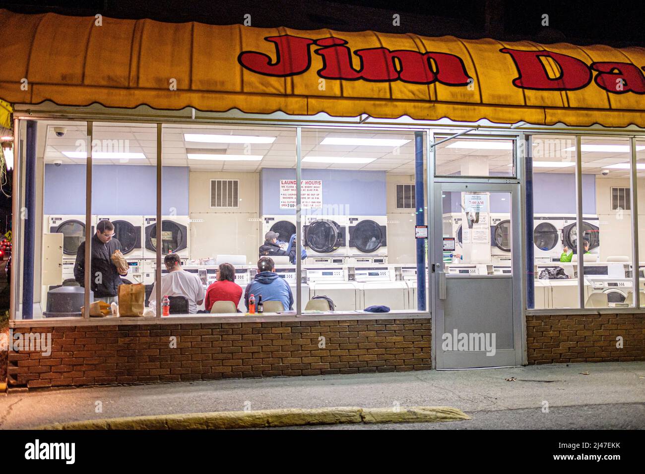 Le persone in attesa dei loro vestiti per lavarsi e asciugare ad una lavanderia automatica in Highland Street a Worcester, Massachusetts Foto Stock