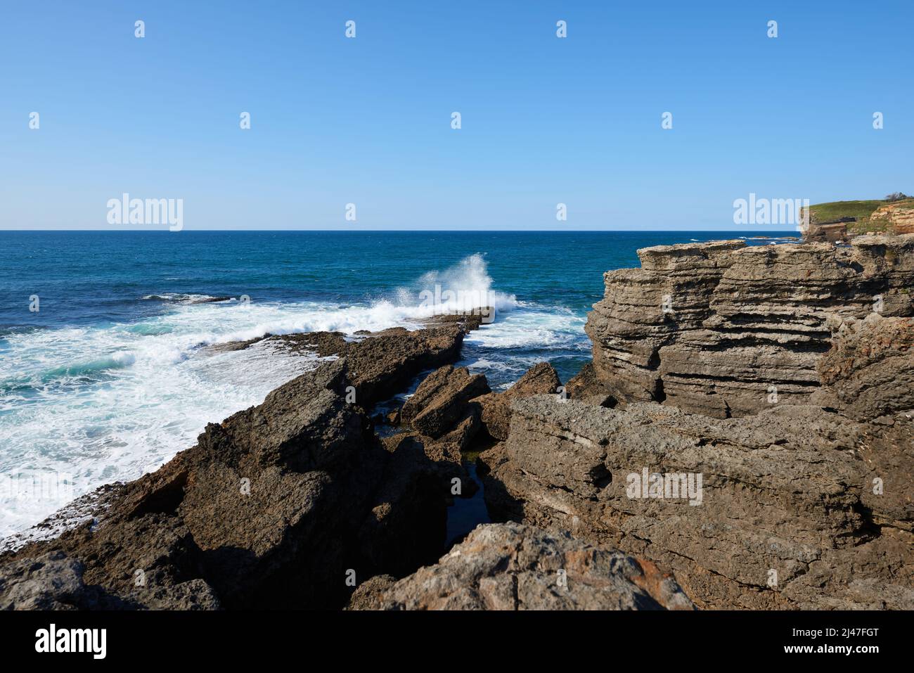 Ripide scogliere con un mare blu profondo e un cielo blu chiaro Foto Stock