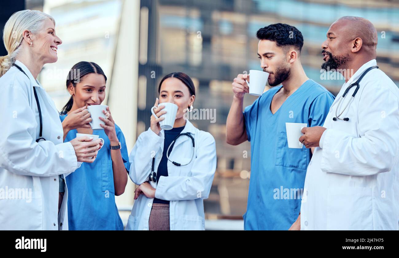 Le lunghe ore di lavoro richiedono una buona tazza di caffè. Shot di un gruppo di medici che bevono caffè in città. Foto Stock