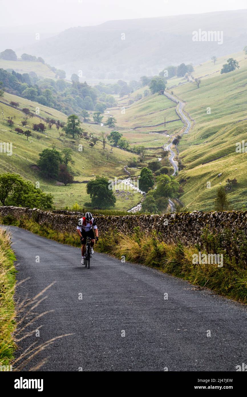 Regno Unito, Inghilterra. Ciclista salendo ripida collina su una giornata autunnale nel Yorkshire Dales. Foto Stock
