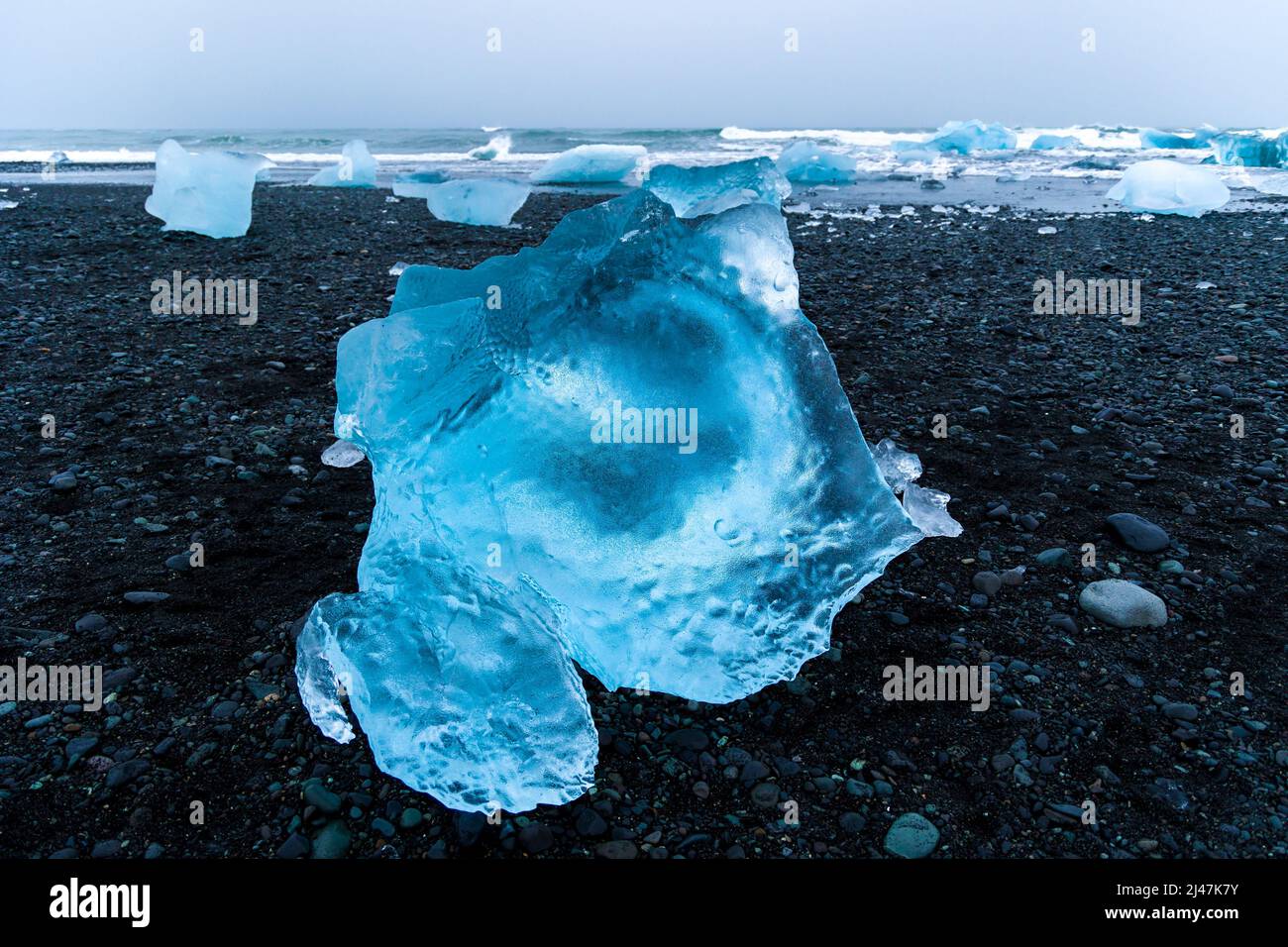 Pezzi di ghiaccio e iceberg rotti su una spiaggia di sabbia nera vulcanica al tramonto (Diamond Beach, Islanda) Foto Stock