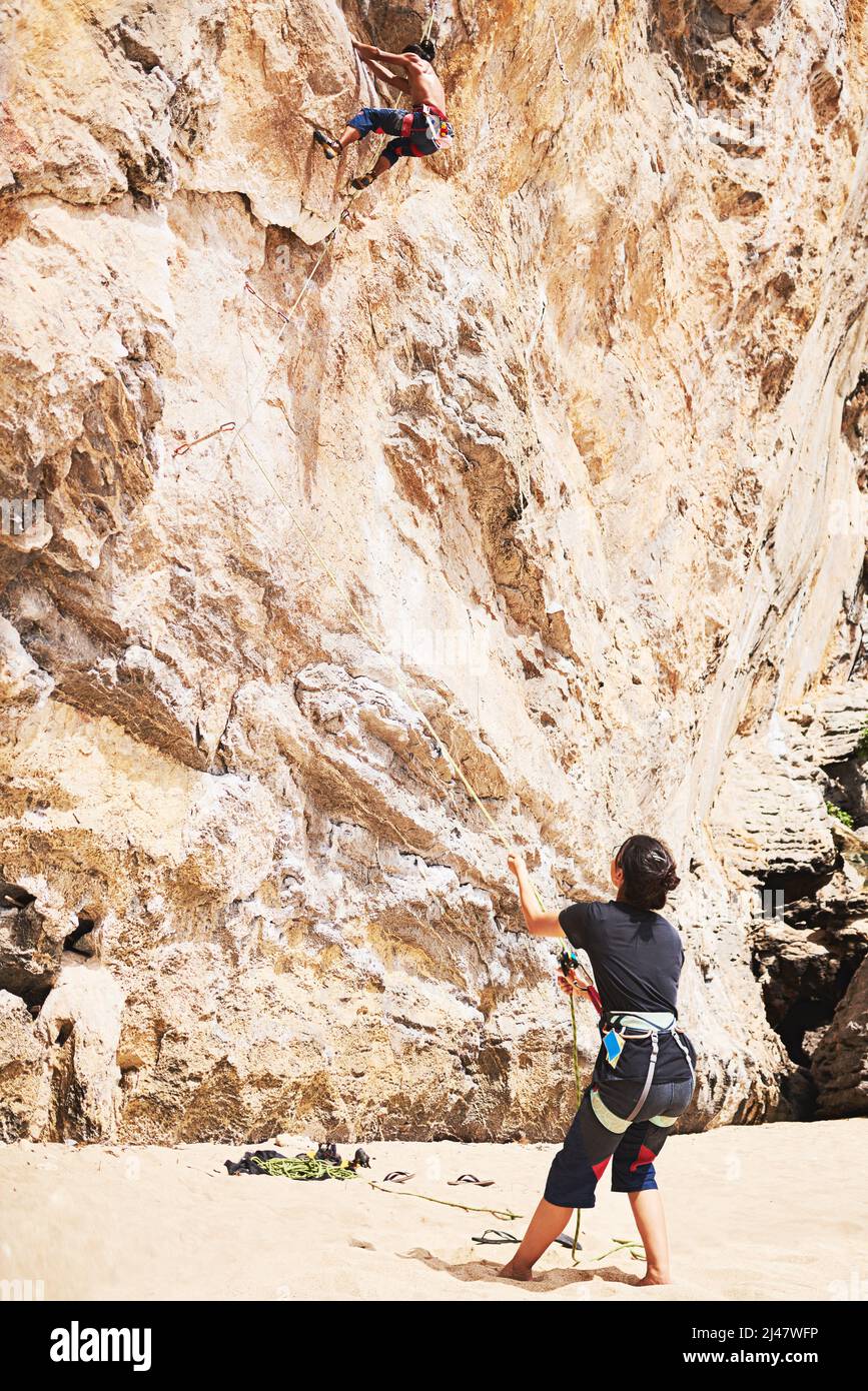Tempo di corda in un'altra avventura. Scatto di due giovani arrampicata su roccia in una giornata di sole. Foto Stock