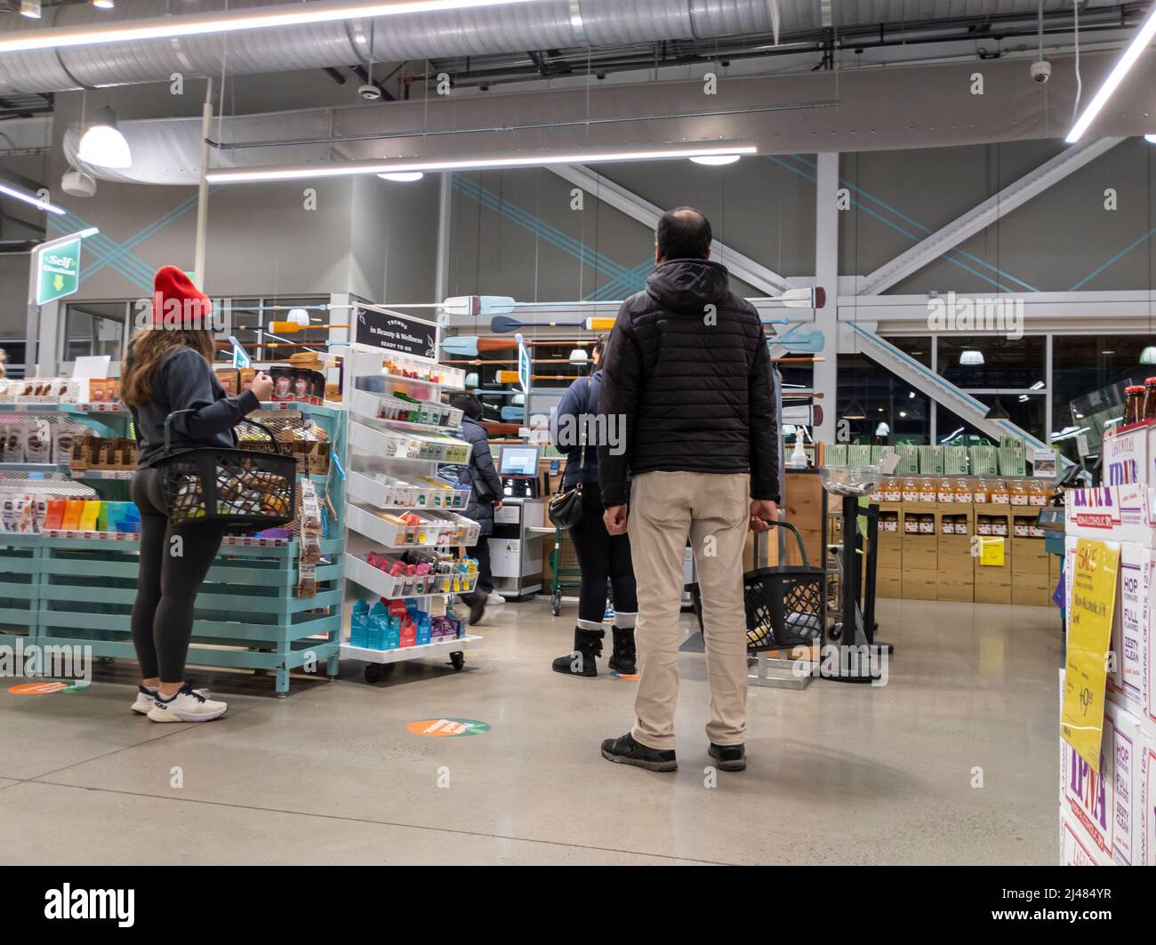 Kirkland, WA USA - circa aprile 2022: Vista di uomini e donne in coda per i chioschi self-check all'interno di un negozio di alimentari Whole Foods. Foto Stock Kirkland, WA USA - circa aprile 2022: Vista di uomini e donne in coda per i chioschi self-check all'interno di un negozio di alimentari Whole Foods. Foto Stock
