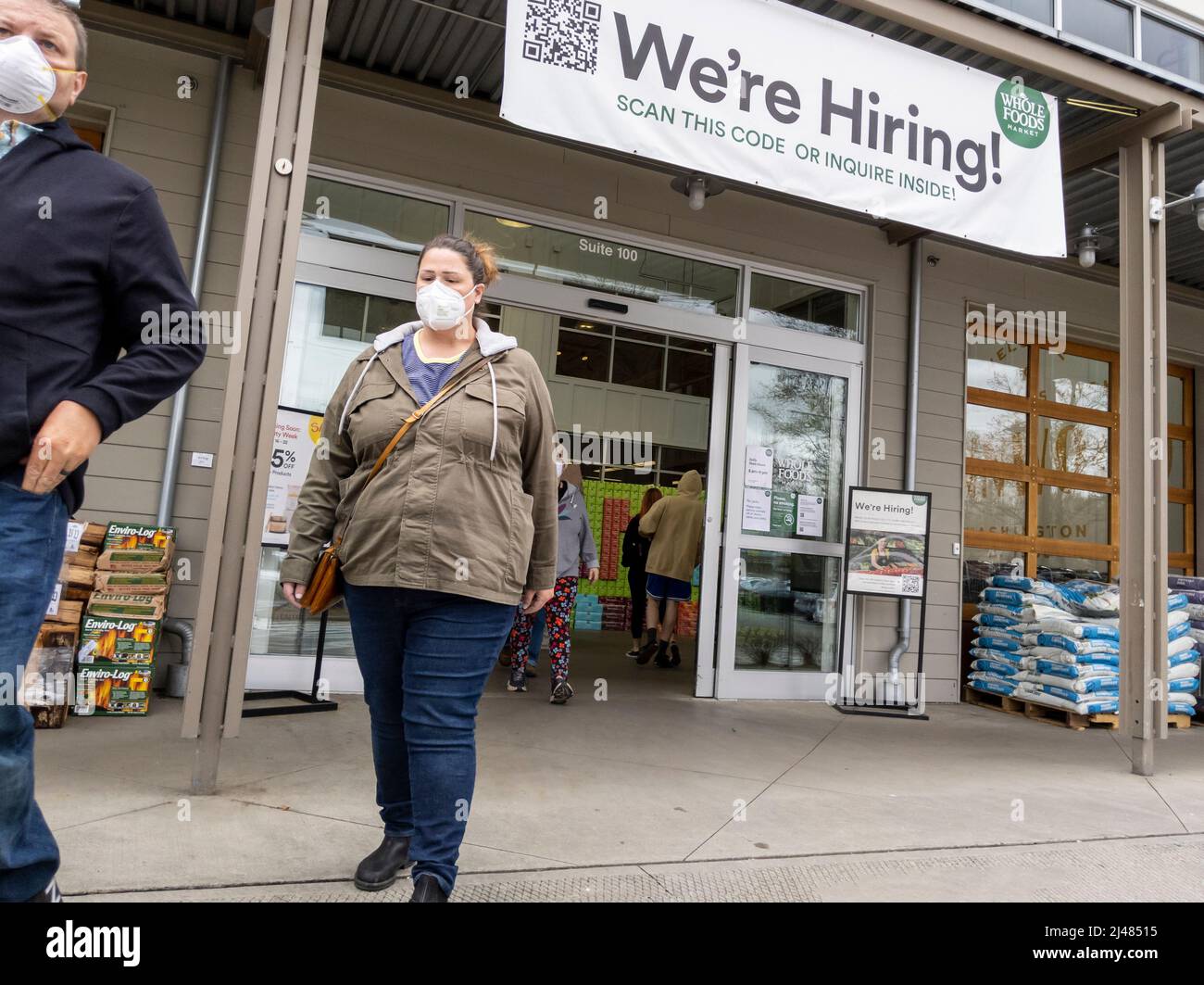Lynnwood, WA USA - circa Aprile 2022: Vista di un cartello We are Hiring all'ingresso di un Whole Foods Market, sopra le persone che entrano ed escono dal negozio Foto Stock Lynnwood, WA USA - circa Aprile 2022: Vista di un cartello We are Hiring all'ingresso di un Whole Foods Market, sopra le persone che entrano ed escono dal negozio Foto Stock