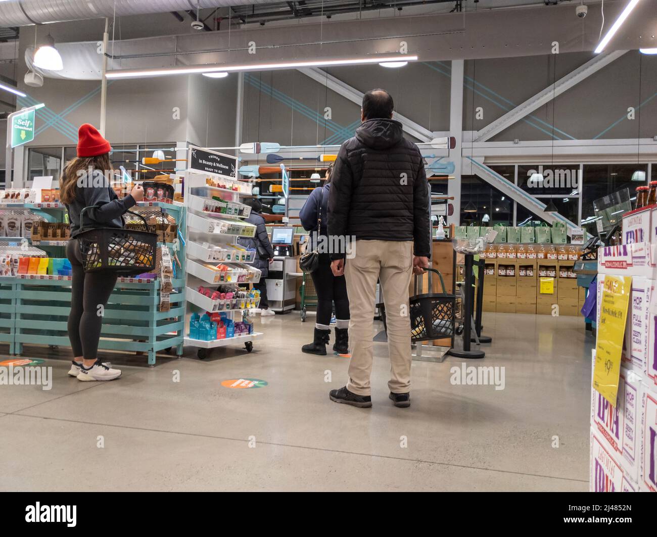 Kirkland, WA USA - circa aprile 2022: Vista di uomini e donne in coda per i chioschi self-check all'interno di un negozio di alimentari Whole Foods Foto Stock Kirkland, WA USA - circa aprile 2022: Vista di uomini e donne in coda per i chioschi self-check all'interno di un negozio di alimentari Whole Foods Foto Stock