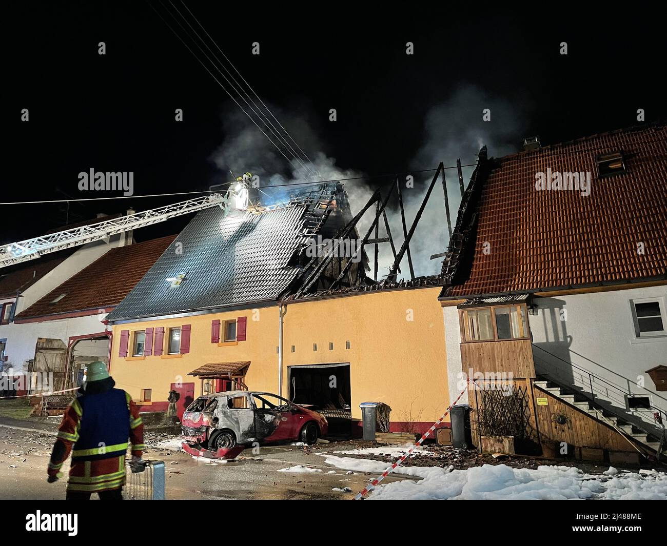 Gomadingen, Germania. 12th Apr 2022. I vigili del fuoco spengono un incendio in un edificio residenziale e fienile. Un incendio in un fienile convertito in un garage a Gomadingen (distretto di Reutlingen) ha causato diverse centinaia di migliaia di euro di danni alla proprietà il martedì sera. Credit: Schulz/Sueddeutsche Mediengesellschaft /dpa/Alamy Live News Foto Stock