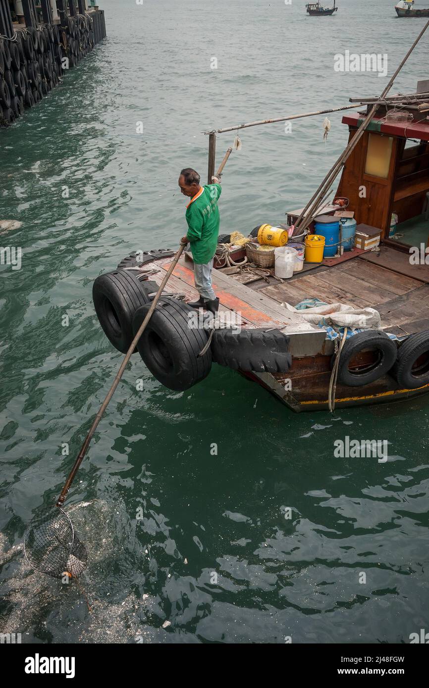 Una piccola spazzatura tradizionale è usata per rimuovere i rifiuti galleggianti dal porto di Victoria vicino ai moli dei traghetti centrali, Hong Kong, 2007 Foto Stock