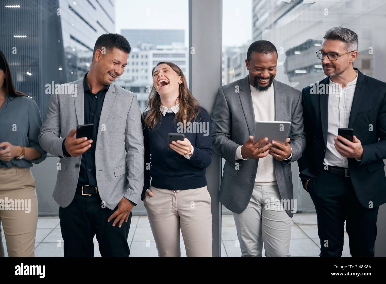 Sociale sia di persona che virtualmente. Scatto di un gruppo di uomini d'affari che utilizzano dispositivi digitali in una sala d'attesa. Foto Stock