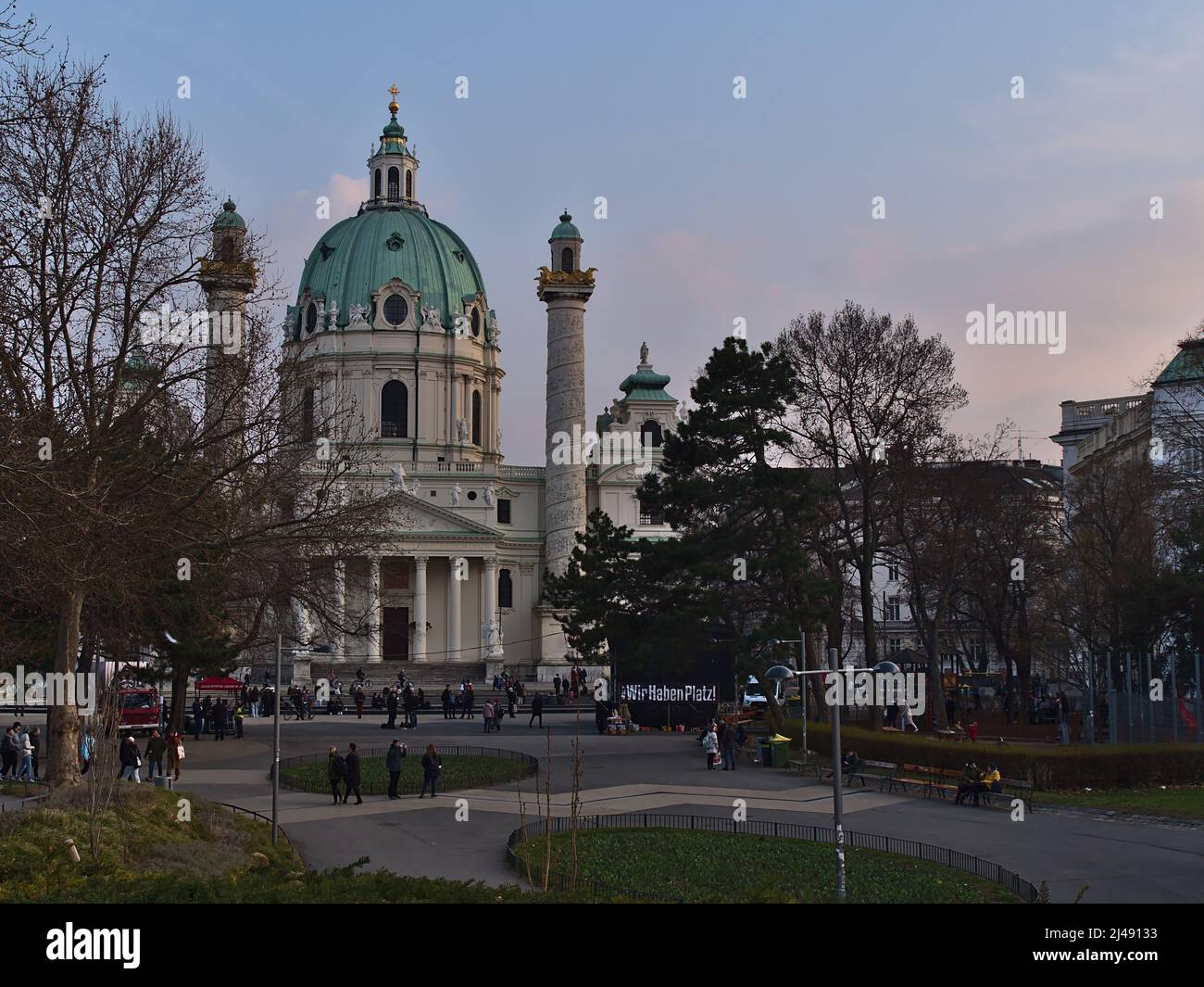 Vista sul parco pubblico Resselpark nel centro storico di Vienna, Austria, con la famosa chiesa Karlskirche e dimostrare la gente in serata. Foto Stock