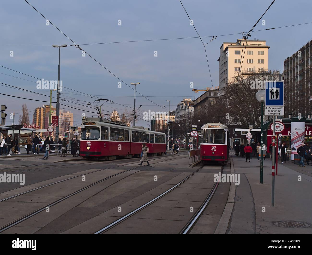 Vista della trafficata stazione del tram Schwedenplatz nel centro di Vienna, Austria, con treni e persone che passano nelle giornate nuvolose nella stagione primaverile. Foto Stock