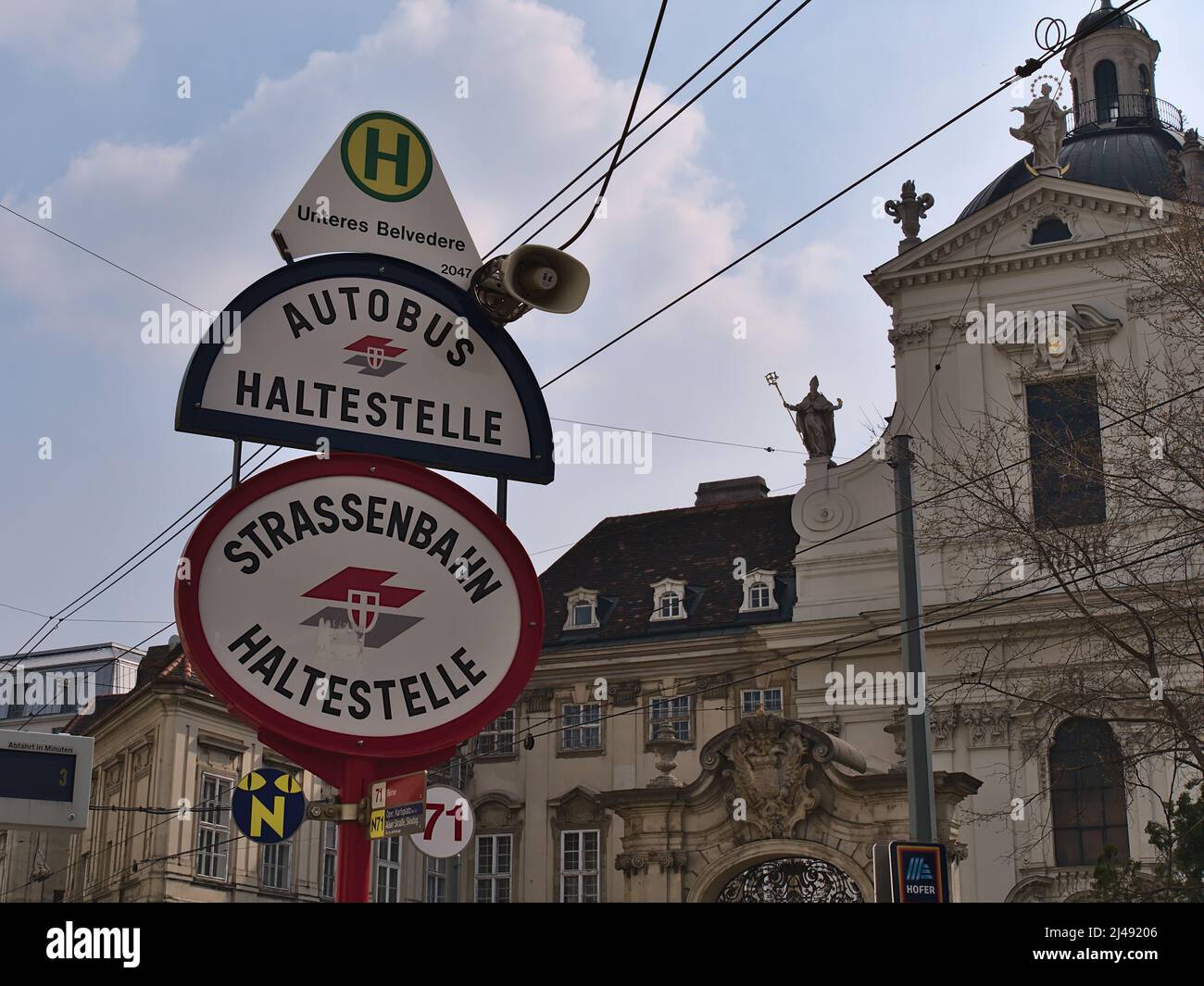 Segnaletica stradale alla stazione degli autobus e del tram Unteres Belvedere nel centro storico di Vienna, Austria con il logo di Wiener Linien e vecchio edificio. Foto Stock