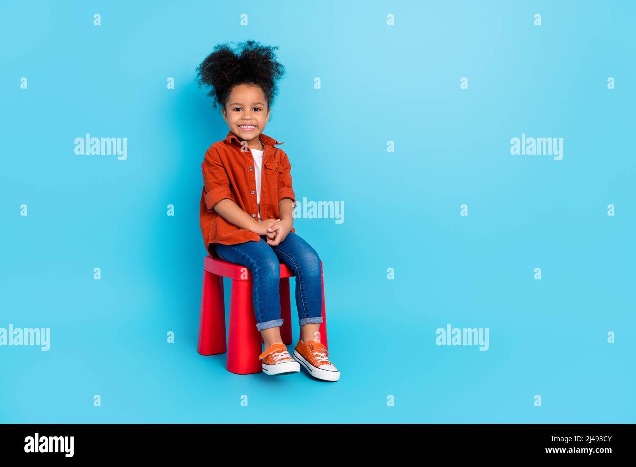 Foto del corpo pieno di simpatico adorabile dolce ragazza sedia seduta passare il tempo in kindergarden isolato su sfondo blu Foto Stock
