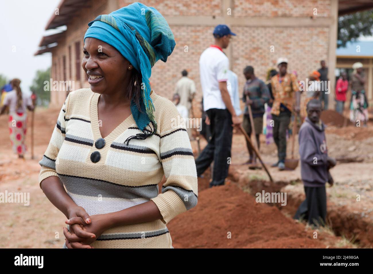 Adria Mukantaguanda, insegnante capo, partecipa al servizio mensile della comunità di Umuganda. Qui stanno lavorando alla costruzione di classi per 12 anni di istruzione di base. La scuola Mwurire Groupe Scolare, Mbazí Sector, Huye District. Fotografia di Mike Goldwater Foto Stock