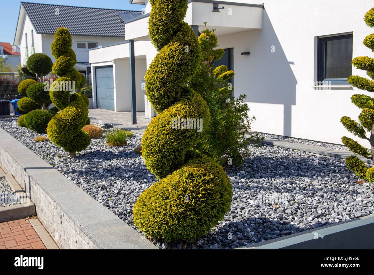 Giardino frontale moderno e ben tenuto con trucioli decorativi e piantagione mediterranea Foto Stock