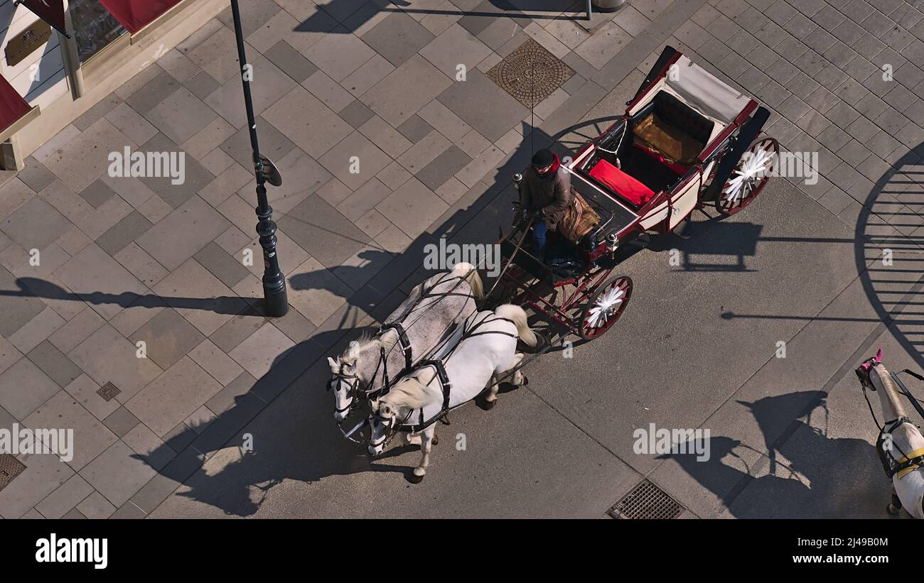 Alto angolo di vista di un fiacre, una carrozza trainata da cavalli a quattro ruote, nel centro storico di Vienna, in Austria, in una giornata di sole con ombre. Foto Stock