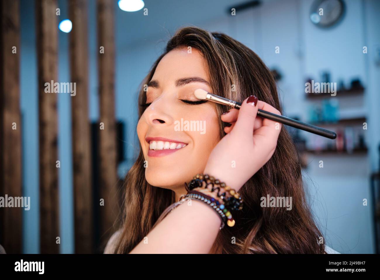 Donna sorridente mentre ottiene il suo trucco fatto nel salone di bellezza. Foto Stock