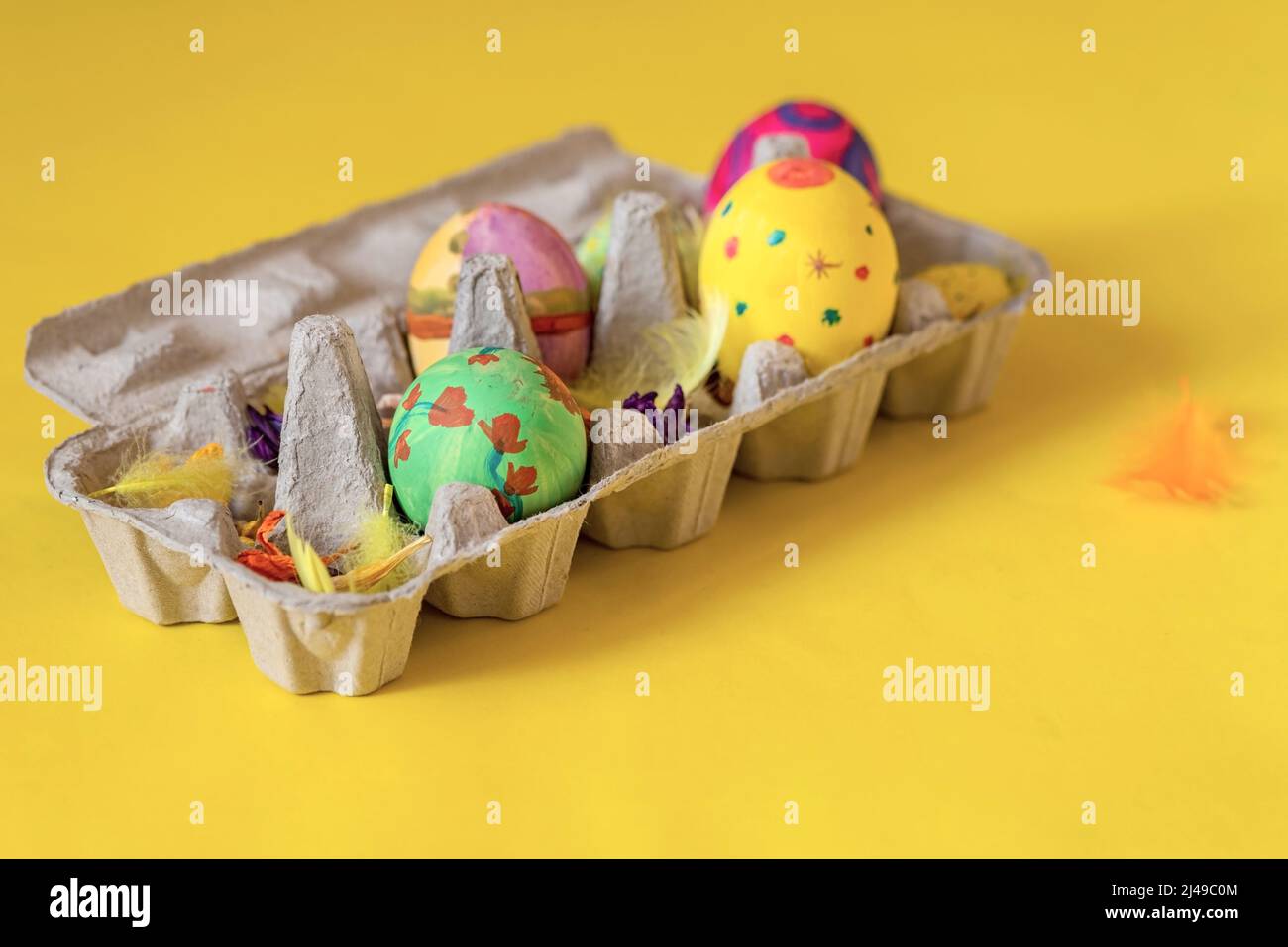 Uova di Pasqua in un cartone di uova su sfondo giallo, primo piano, isolato Foto Stock