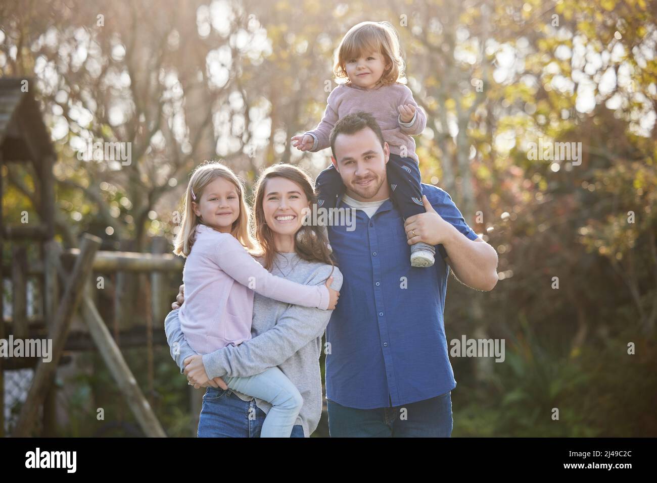 La famiglia perfetta. Ritratto corto di una giovane famiglia affettuosa di quattro in posa nel giardino di casa. Foto Stock