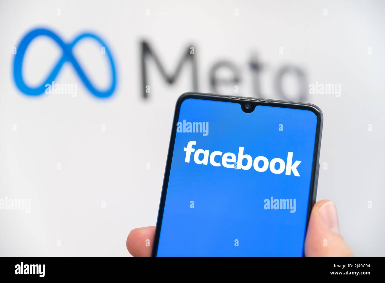 Wroclaw, Polonia - Apr 01, 2022: Facebook cambia il nome della sua azienda in Meta. Facebook su uno smartphone e logo Meta sullo sfondo Foto Stock