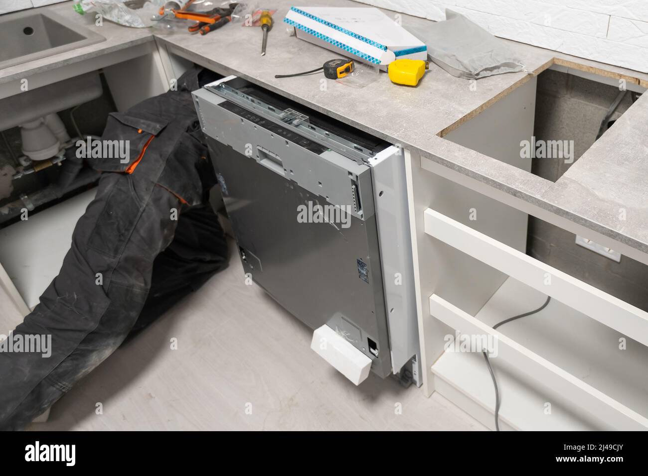 Tecnico di apparecchi che lavora sotto un lavello della cucina installando una  lavastoviglie Foto stock - Alamy