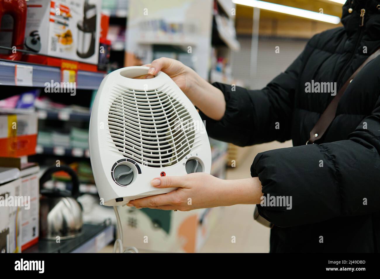 Cliente donna che sceglie il riscaldatore a ventola elettrica nel negozio di forniture per l'edilizia. Primo piano. Foto Stock