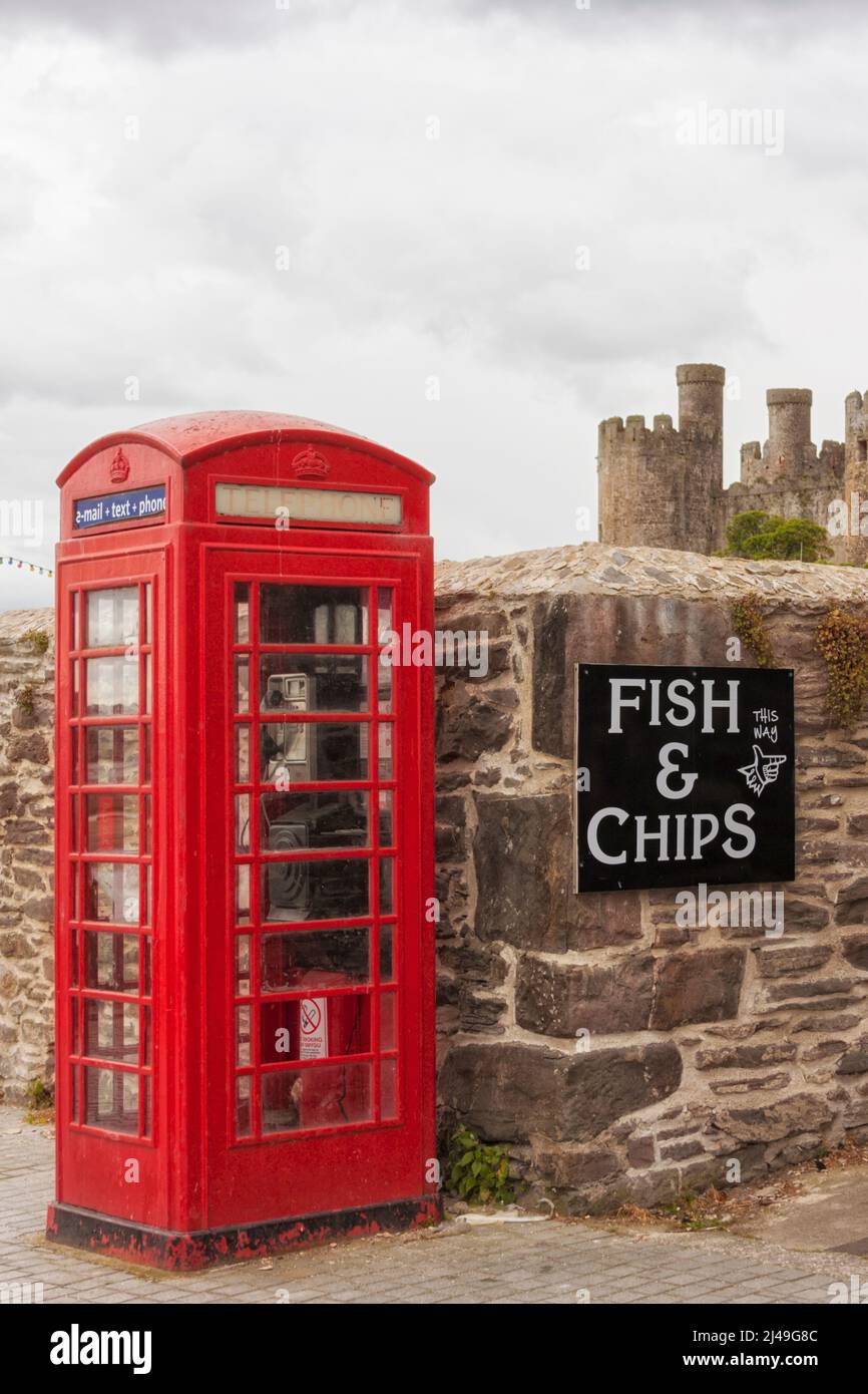 Clichés della Gran Bretagna: Cabina telefonica rossa, mura del castello, segno di fish and chips, cielo stellato. Foto Stock